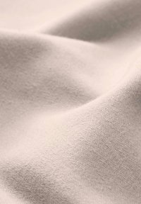 Lichtbeige katoen stof met een gladde textuur, voorzien van een subtiel ribbelpatroon en zachte plooien. Zachte, matte afwerking.