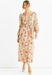 Floral wrap dress in light beige with red and blue patterns. Features long puff sleeves and a tied waist. Smooth, lightweight fabric.