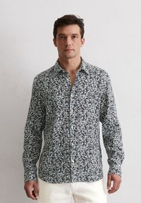 Herren Hemd mit langen Ärmeln aus leichtem Stoff mit dunklem floralen Muster in Grün-, Blau- und Grautönen. Knopfleiste mit klassischem Kragen.