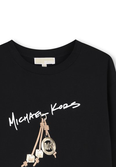 Μαύρο πουκάμισο με λευκό λογότυπο Michael Kors και χρυσό γούρι MK κάτω από το κείμενο μπροστά κοντά στον λαιμό.