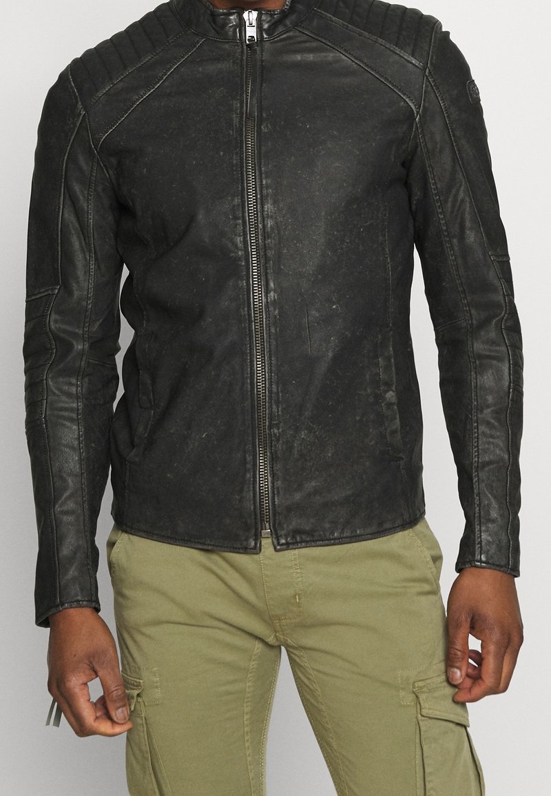 Czarna skórzana kurtka motocyklowa z prążkowanymi detalami na ramionach, gładką fakturą, przednim zamkiem błyskawicznym i dopasowanym krojem.