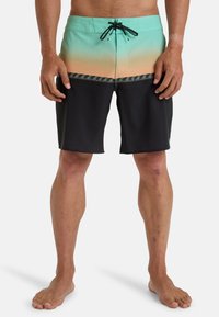 Shorts de bain pour homme en teal et noir, présentant un dégradé, une ceinture contrastante et un motif décoratif près de l'ourlet.