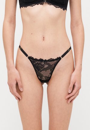 String noir en dentelle avec des motifs floraux complexes, des sangles latérales réglables, une couverture minimale et des bords festonnés.