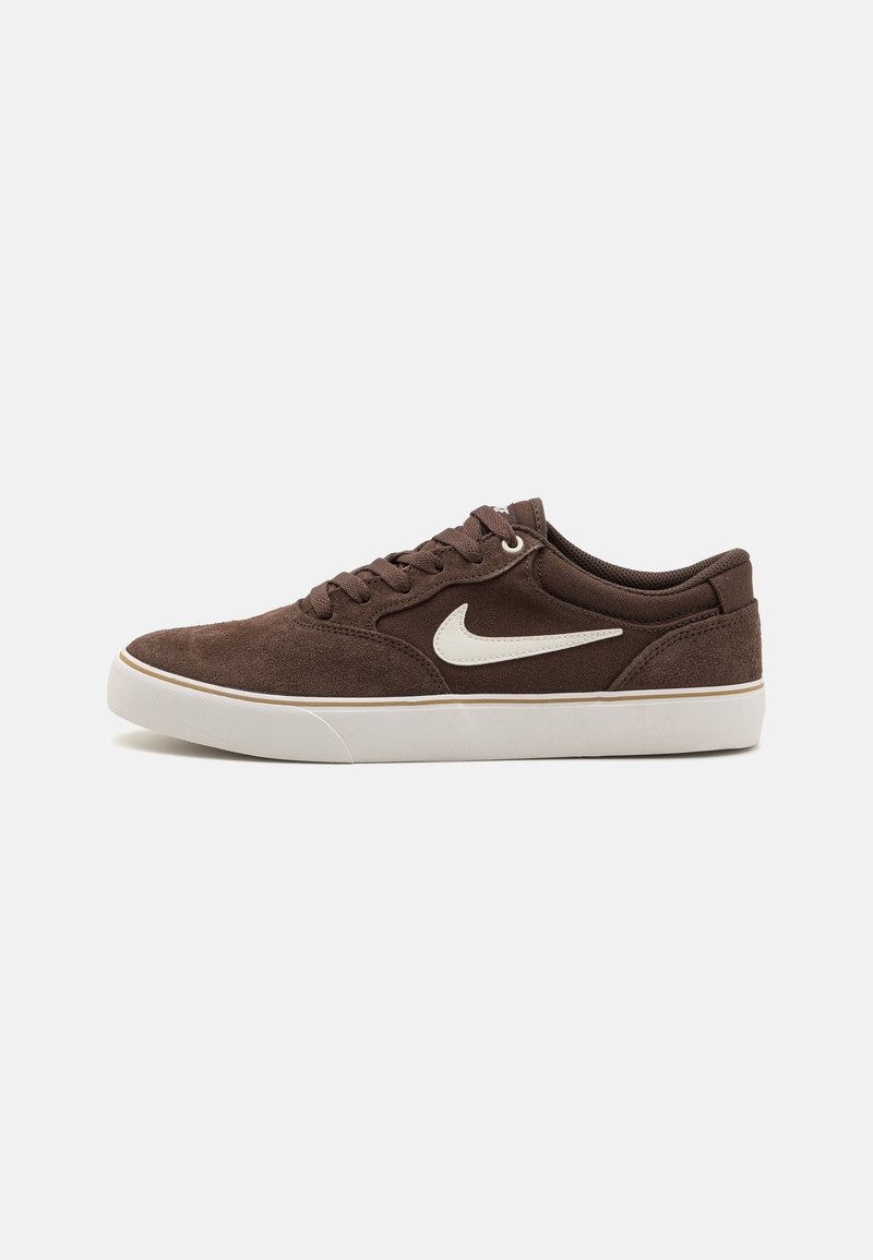Baskets basses en daim marron avec logo Nike swoosh blanc et semelle en caoutchouc blanche, vues de côté sur un fond clair.