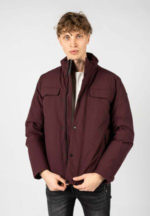 Chaqueta acolchada burdeos con alto cuello, cierre frontal a presión, dos bolsillos en el pecho y cremalleras laterales. Textura suave, diseño casual.