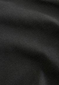 Schwarzer Stoff mit einer glatten, strukturierten Oberfläche, die ein feines geripptes Muster aufweist, sanfte Falten und Lichtreflexionen zeigt.