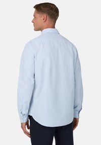 Camicia a maniche lunghe di colore azzurro chiaro con strisce bianche, con polsini abbottonati e orlo curvo. Realizzata in tessuto di cotone testurizzato.