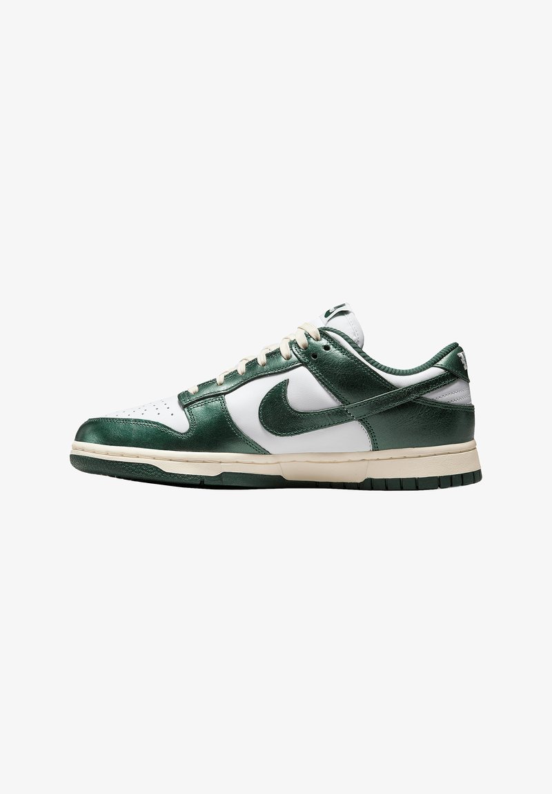 Nike Dunk Low sneakers con parte superiore in pelle verde e bianca, texture liscia, suola in gomma e puntale perforato. Design classico.