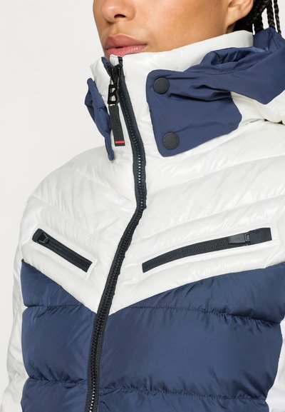 Μπουφάν με γέμισμα και ψηλό γιακά, με σχέδιο σε χρώματα μπλε ναυτικού και λευκού, έχων κλειστές τσέπες με φερμουάρ και εμπρόσθια κλεισίματα με φερμουάρ.