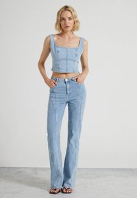 Cropped top in denim azzurro con scollo quadrato e vestibilità slim abbinato a jeans a vita alta in denim azzurro con dettagli di cucitura intricati.