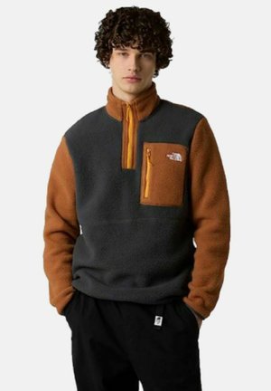 Sudadera de forro polar con cuerpo gris y mangas naranjas, que presenta un cierre de cremallera en el pecho y un bolsillo en el pecho con cremallera.