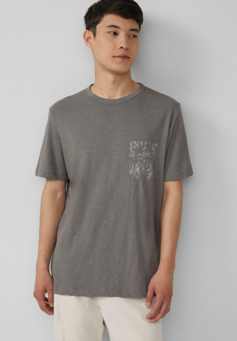 Grijze t-shirt met korte mouwen, gemaakt van zacht stof, met een borstzakje met een subtiele botanische print. Ontspannen pasvorm en ronde hals.