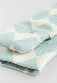 Világoskék és krémszínű mintás szövet, bordázott textúrával, geometrikus kialakítással és hajtott szélekkel.