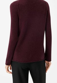 Pull à manches longues bordeaux en tissu doux, avec un ourlet légèrement arrondi et des poignets côtelés, vue de dos.