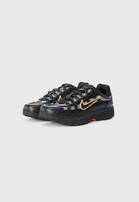 Chaussures de sport noires avec des accents jaunes contrastants, une tige texturée et des semelles rembourrées, dotées de lacets et d'éléments de marque.