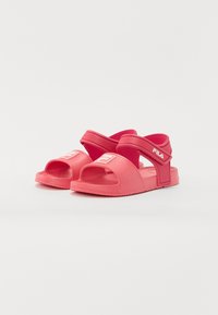 Sandale roz din cauciuc cu un design cu vârful deschis, curea cu arici și talpă texturată. Prezintă un logo alb pe partea din față și lateral. Construcție ușoară.