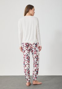 Μακρυμάνικο λευκό μπλουζάκι συνδυασμένο με πυτζάμες με floral σχέδιο σε κόκκινο, ροζ και μπλε σε ανοιχτό φόντο. Μαλακό ύφασμα, χαλαρή εφαρμογή.