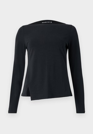 Black long-sleeve top made from smooth fabric, featuring a high neckline and an asymmetric hem with side slits for a modern design.