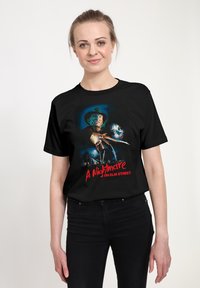 Černé tričko s barevnou grafickou ilustrací hororov�é filmové scény, na které je tvář postavy a text názvu níže.