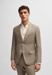 Light brown linen suit featuring a single-breasted jacket with notched lapels, two front pockets, and a matching pair of trousers.