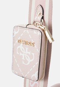 Porte-cartes en matériau synthétique rose avec quincaillerie dorée, logo en relief et accents à motifs blancs. Dispose d'une fermeture zippée et d'une bandoulière détachable.