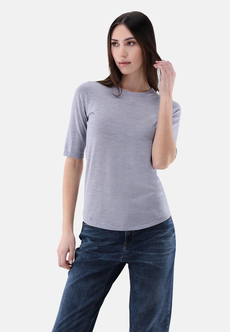 Helles graues, kurzärmliges Oberteil mit Rundhalsausschnitt, aus einem weichen Material gefertigt. Kombiniert mit dunkelblauen, leicht lockeren Jeans.