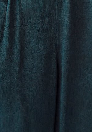 Žalsvai melsvas audinys su tekstūruota, raukšlėta paviršiaus struktūra, kuriame matomos subtilios blizgesio ir rašto variacijos, tinkamas drabužiams ar minkštiems baldams.