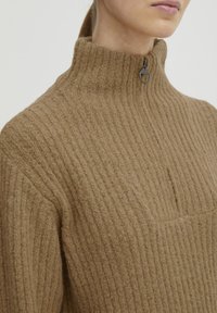 Pulover bej cu modele în dungi, cu guler înalt, având un închidere cu jumătate de fermoar și detalii de cusătură subtile. Fabricat din material tricotat texturat.