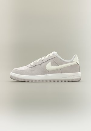 Χαμηλό sneaker Nike από ανοιχτό γκρι σουέντ με λευκό λογότυπο Swoosh, λευκά κορδόνια και λευκή σόλα σε ουδέτερο φόντο.