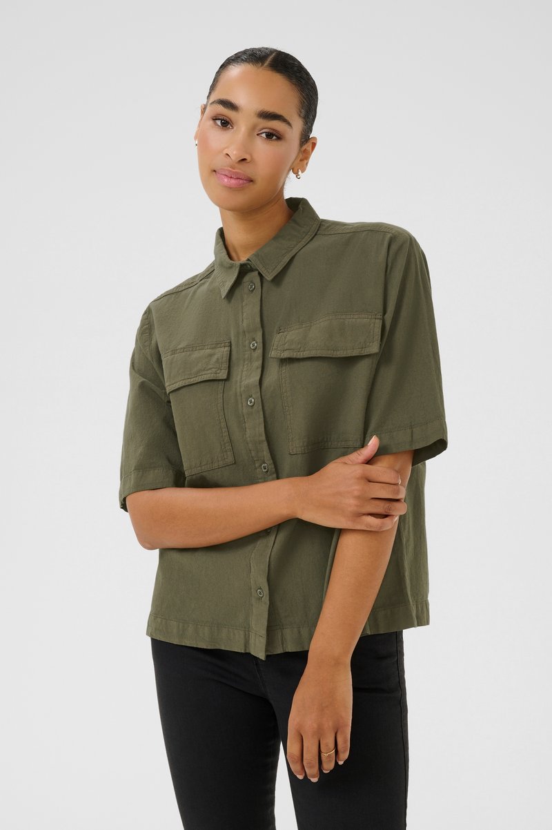 Chemise à manches courtes olive verte avec deux poches poitrine, un col, et une coupe décontractée, fabriquée dans un tissu léger.