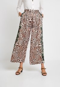 Spodnie z szerokimi nogawkami w grochy w leopardzie, z zielonym wzorem liści, posiadające wysoki stan, zaszewki oraz boczne kieszenie. Wykonane z lekkiego materiału.