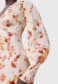 Abito floreale in tessuto leggero con uno sfondo crema morbido e motivi di fiori multicolori. Maniche a sbuffo con polsini smock.