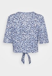 Top corto floreale in tonalità di blu con maniche corte, dotato di un fiocco all'orlo. Tessuto morbido e leggero con un delicato motivo floreale.
