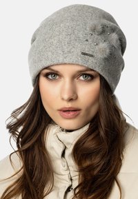 Szary wełniany beanie z puszystymi pomponami i zdobieniami. Luźny krój; miękka tekstura. Zawiera metkę z logo. Odpowiedni na zimę.