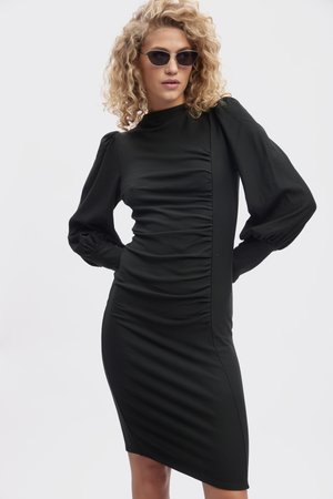 Black fitted dress with long puff sleeves, side ruching, and a high neckline. Smooth texture and knee-length design. Accentuated silhouette.