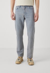 Vaqueros de denim azul claro con corte recto. Cuentan con cinco bolsillos, cierre frontal de botón y una textura ligeramente desvaída.