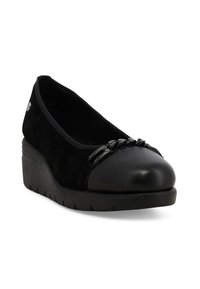 Scarpe con tacco a cuneo nere con punta liscia, parte superiore in suede e dettaglio decorativo in catena nera sulla parte anteriore.