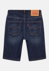 Tmavé džínové šortky se rovný střihem, s hnědou koženou etikou, dvěma zadními kapsami a kontrastním prošíváním.