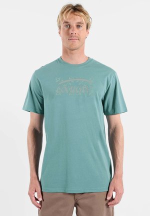 T-shirt en coton bleu sarcelle à manches courtes, avec un logo Oxbow discret dans une teinte plus claire. Coupe décontractée avec un col rond.