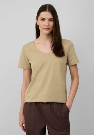 Tan V-hals T-shirt van lichtgewicht katoen, met korte mouwen en een relaxte pasvorm. Gecombineerd met een bruine broek, voor een neutrale achtergrond.