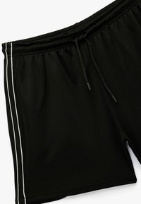 Pantalones cortos deportivos negros fabricados en un tejido texturizado, con una cintura elástica, cordón y franjas laterales blancas para dar contraste.