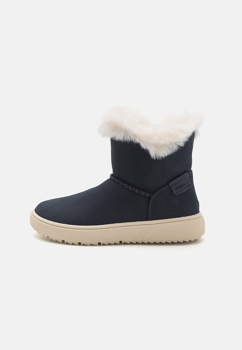 Botte d'hiver noire avec semelle beige et doublure en fourrure blanche visible au bord supérieur, vue de côté sur fond blanc uni.