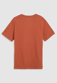 T-shirt uni de couleur rouille à manches courtes, vu de dos avec un col rond sur un fond clair.