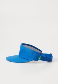 Visor de tecido azul com uma aba curva larga e uma correia ajustável com uma etiqueta verde. Textura suave e design minimalista.