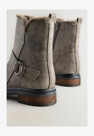 Graue Knöchelstiefel mit einem weichen Fellfutter, aus Leder, mit runden Zehen, Reißverschluss und einem gestapelten Holzabsatz; mit einem dekorativen Riemen.