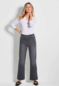 Pantalon en denim gris à jambes larges avec une taille élastique et des poches avant, associé à un haut à manches longues blanc. Design simple, texture lisse.