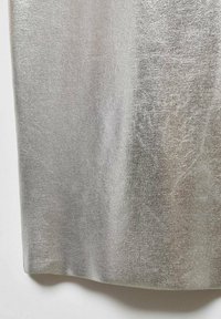 Tissu argenté métallique avec une surface lisse et texturée. Présente un éclat subtil et une tombée douce, taillé dans une forme douce et fluide.
