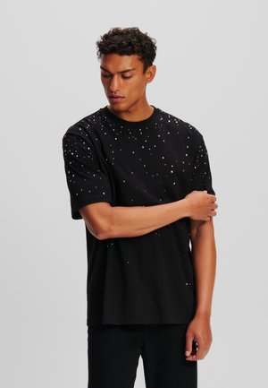Black cotton t-shirt with short sleeves, featuring scattered silver embellishments. Relaxed fit with a crew neck and plain hem.