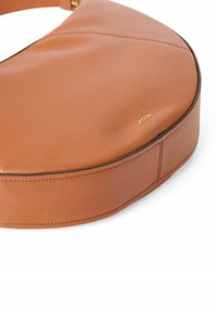 Brun læderhandtaske med en halvmåneform, tekstureret overflade og diskret syning. Har guldhardwaredetalje i hjørnet.