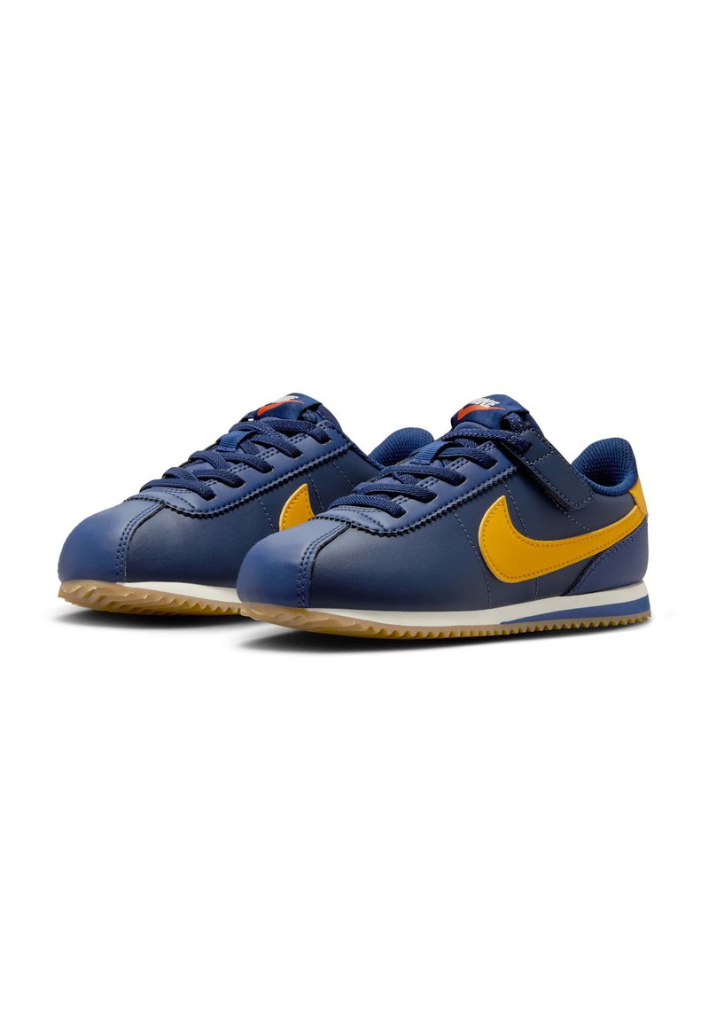 Baskets Nike en cuir bleu marine avec des accents jaunes. Elles possèdent un design à lacets, une semelle en caoutchouc texturée et des détails cousus.